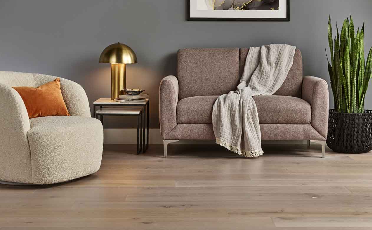 Hardwood flooring in a living room with brown loveseat and cream accent chair
